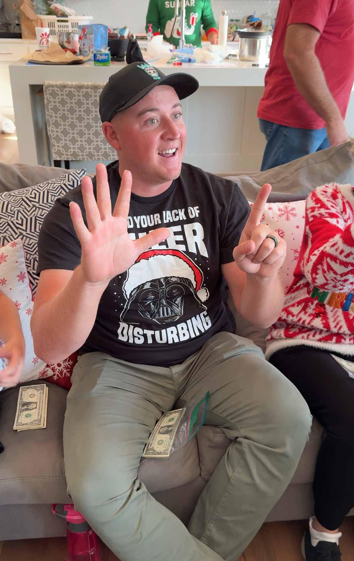 A man holding up 6 fingers for the Christmas price is right game