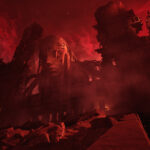 A towering structure erected in the image of an emaciated face under a cloudy, bright red sky in The Forever Winter, highlighting the game's desolate post-apocalyptic atmosphere