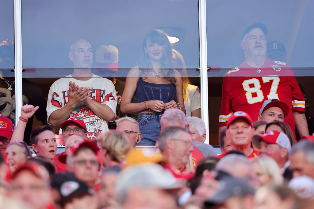 KANSAS CITY, MISSOURI - SEPTEMBER 05: Taylor Swift watches as the Kansas City Chiefs take on the Baltimore Ravens during the first quarter at GEHA Field at Arrowhead Stadium on September 05, 2024 in Kansas City, Missouri. (Photo by David Eulitt/Getty Images), lwymmd boots, guiseppe zanotti red boots, versace denim medusa 95 bustier corset top