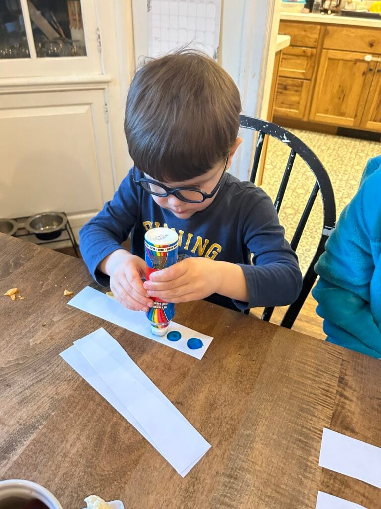 Child creating colorful patterns on paper strips for the Order Up Game