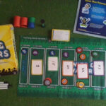 Wits and Wagers board game, showing the betting mats and chips arranged on a table, surrounded by players.