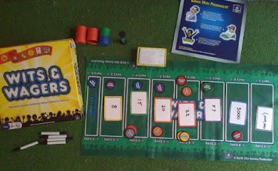 Wits and Wagers board game, showing the betting mats and chips arranged on a table, surrounded by players.