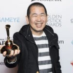Yu Suzuki holds his Lifetime Achievement award in 2019